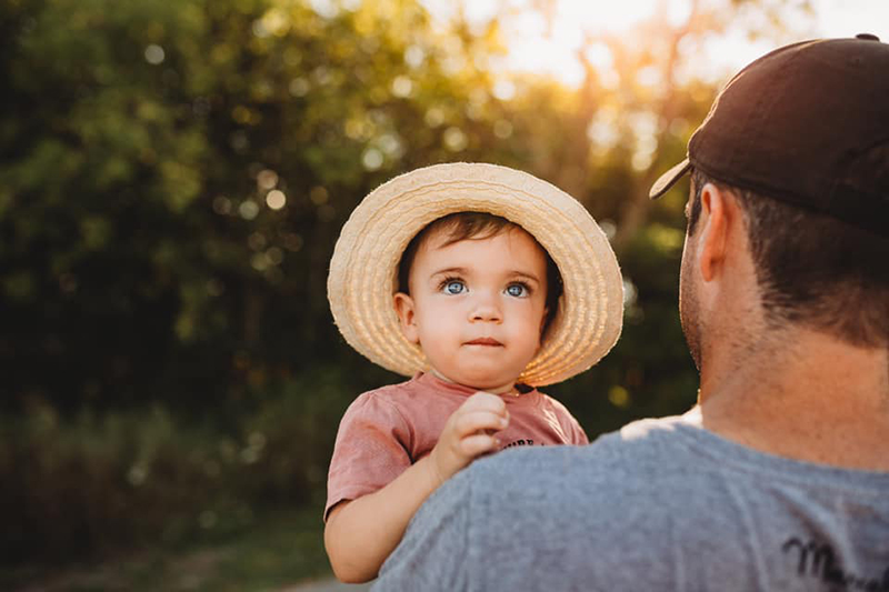Father and baby in hat outside in golden hour