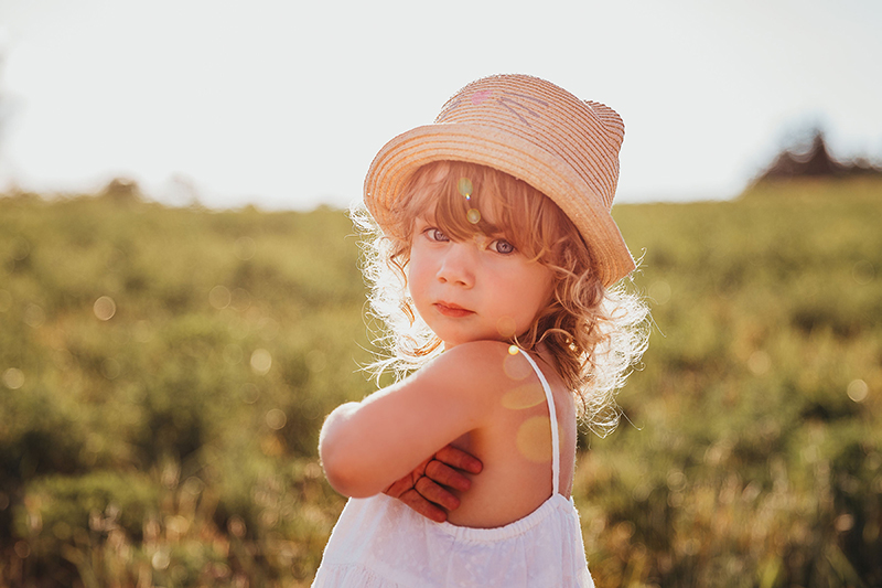 child wearing hat and white dress outdoors